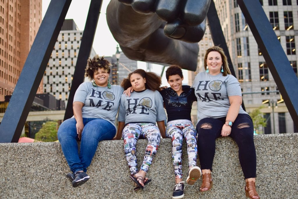 Liv, Clara, AJ and Carissa wearing Detroit Has Legs T-shirts and leggings in front of the Monument to Joe Louis, Hart Plaza Detroit