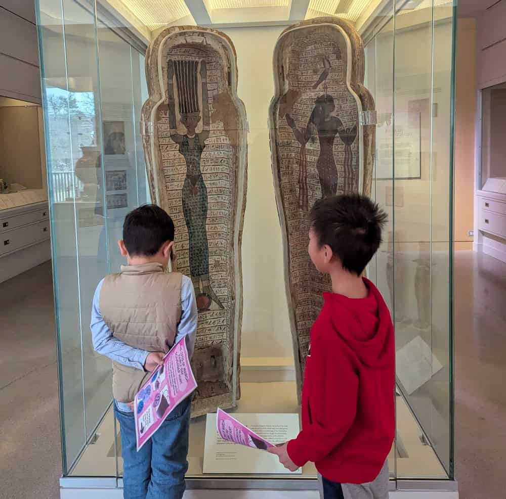 two boys looking at an ancient egyptian mummy