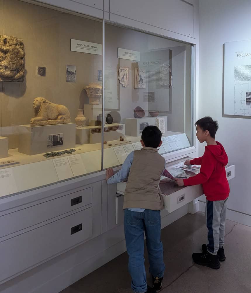 a group of boys looking at a display case at the Kelsey Museum of Archaeology in Ann Arbor