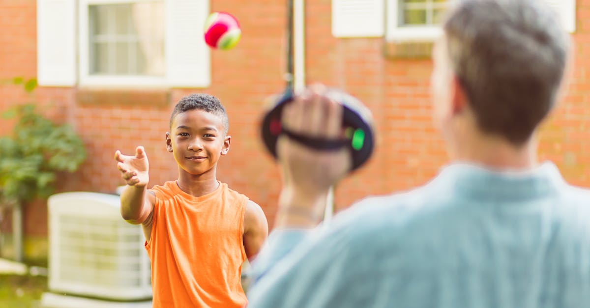 Fun Ways to Encourage Kids to Spend More Time Outside 3 Young boy in orange tank top playing catch outdoors on a sunny day.